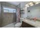 Bathroom with granite countertop vanity, tile shower, updated fixtures, and natural light at 1433 Spring Ln, Clearwater, FL 33755