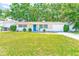Charming single-story home featuring a bright blue front door, well-manicured lawn and attached garage at 1433 Spring Ln, Clearwater, FL 33755