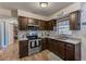Well-lit kitchen featuring granite countertops, dark cabinets, stainless steel appliances, and wood-look floors at 1433 Spring Ln, Clearwater, FL 33755