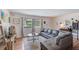 Bright living room with wood-look flooring, a large sectional sofa, and three big windows at 1433 Spring Ln, Clearwater, FL 33755
