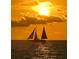 Sailboat sailing on the ocean at sunset, with a golden sky and glistening water at 1480 Gulf Blvd # 1004, Clearwater Beach, FL 33767