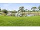 Scenic view of a tranquil pond surrounded by lush green grass and mature trees at 1532 Citrine Trl, Tarpon Springs, FL 34689