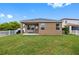 Well-kept backyard showcasing a lovely covered patio, pristine green lawn, and classic white picket fence at 1811 Redmond Brook Ln, Ruskin, FL 33570