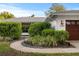 Exterior view of home with walkway, lush shrubbery, and two-car garage at 2665 Clubhouse N Dr, Clearwater, FL 33761