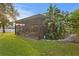 View of a spacious screened-in lanai with dining and seating areas, surrounded by lush landscaping at 2665 Clubhouse N Dr, Clearwater, FL 33761