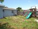 A backyard with a wooden fence, a playset featuring a slide and swing set, and space for outdoor activities at 3424 Truman Dr, Holiday, FL 34691