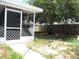 Backyard featuring a screened porch, grassy area, and a wooden fence at 3424 Truman Dr, Holiday, FL 34691