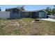 A single-story home featuring blue exterior paint, a driveway, a white fence, and a lawn at 3424 Truman Dr, Holiday, FL 34691