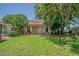 Quaint brick home featuring a well-kept front lawn, mature trees, and a cozy porch at 35058 Whispering Oaks Blvd, Dade City, FL 33523