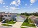 Aerial shot of neighborhood homes, manicured lawns, landscaping, and a serene pond backdrop under a blue sky at 36673 Spanish Rose Dr, Dade City, FL 33525