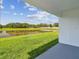 A view from the back porch showing a well-manicured lawn and a large pond surrounded by trees at 36673 Spanish Rose Dr, Dade City, FL 33525