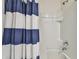 Close-up of shower-tub combo with white tile and a blue-striped shower curtain in the home's bathroom at 36673 Spanish Rose Dr, Dade City, FL 33525
