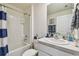 Bathroom featuring a shower-tub combo with white tile, blue-stripped shower curtain, and a single sink vanity at 36673 Spanish Rose Dr, Dade City, FL 33525