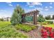 Community sign: Heritage Hills featuring lush landscaping, green shrubs and colorful red flowers at 36673 Spanish Rose Dr, Dade City, FL 33525