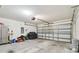 Spacious garage featuring a garage door, lawn equipment, and ample storage at 36673 Spanish Rose Dr, Dade City, FL 33525