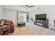 Carpeted living room showing a fireplace with a TV, leather sofa and a leather ottoman at 36673 Spanish Rose Dr, Dade City, FL 33525