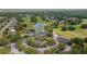 Aerial view of community clubhouse and golf course; features pond with fountain, mature trees, and parking at 5182 Championship Cup Ln, Spring Hill, FL 34609