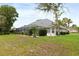 Expansive backyard featuring a screened-in patio, manicured shrubs, and lush green lawn at 5182 Championship Cup Ln, Spring Hill, FL 34609