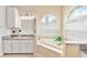 Granite countertops, dual sinks, vanity, and soaking tub with tile surround are featured in this bright bathroom at 5182 Championship Cup Ln, Spring Hill, FL 34609