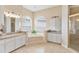 Well-lit bathroom featuring a soaking tub with tile surround, dual sinks, a linen closet, and a glass enclosed shower at 5182 Championship Cup Ln, Spring Hill, FL 34609