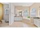 Bright bathroom with double sinks, granite countertops, and soaking tub under arched window with blinds at 5182 Championship Cup Ln, Spring Hill, FL 34609