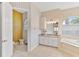 Dual sinks, granite countertops, and a soaking tub with tile surround can be seen in this well-lit bathroom at 5182 Championship Cup Ln, Spring Hill, FL 34609