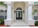 Grand entrance with decorative glass double doors, flanked by white columns and stylish outdoor sconces at 5182 Championship Cup Ln, Spring Hill, FL 34609
