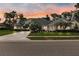Well-manicured front exterior featuring a large driveway, mature landscaping, and a vibrant sunset at 5182 Championship Cup Ln, Spring Hill, FL 34609