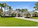 Stately single-story home boasts a manicured lawn, complemented by mature palm trees and a circular driveway at 5182 Championship Cup Ln, Spring Hill, FL 34609