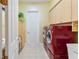 Laundry room with red washer and dryer, storage cabinets, and tiled floor at 5182 Championship Cup Ln, Spring Hill, FL 34609