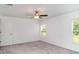 Spacious bedroom with neutral carpet, ceiling fan, and windows offering natural light and backyard views at 5518 Blue Azure Dr, Wimauma, FL 33598