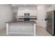 Bright kitchen featuring white cabinets, stainless steel appliances, and a spacious island with a stone accent wall at 5518 Blue Azure Dr, Wimauma, FL 33598