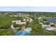 Expansive aerial view highlighting a community with tennis courts and a pool nestled among lush trees and a lake at 568 Shoreham Ne Ct, St Petersburg, FL 33716