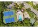 An aerial view of tennis courts, a swimming pool, and a basketball court surrounded by mature trees and lush foliage at 568 Shoreham Ne Ct, St Petersburg, FL 33716