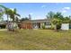 Nicely landscaped front yard features mature palm trees, green lawn, and a covered drive at 6698 35Th N Ave, St Petersburg, FL 33710