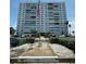 Multi-story condo building with manicured landscaping and an American flag, set against a clear blue sky at 7200 Sunshine Skyway S Ln # 2E, St Petersburg, FL 33711