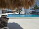 Condo community pool with lounge chairs, tiki huts and direct sunlight, and palm trees at 7200 Sunshine Skyway S Ln # 2E, St Petersburg, FL 33711