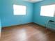 A blue bedroom featuring wood flooring and dual windows with blinds at 888 Forest Glen Rd, Clearwater, FL 33765