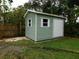 Exterior view of the backyard shed, featuring a rolling door, window, and painted siding at 888 Forest Glen Rd, Clearwater, FL 33765