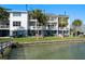Exterior waterfront view of a multilevel home, featuring balconies, and a lush green lawn by the water at 9939 1St E St, Treasure Island, FL 33706