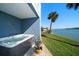 Inviting hot tub area with waterfront view, and patio seating, under a covered patio area with palm trees at 9939 1St E St, Treasure Island, FL 33706