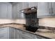 Modern kitchen with stainless cooktop and marble backsplash, light grey cabinets, and granite countertops at 9939 1St E St, Treasure Island, FL 33706