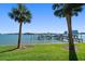 A serene waterfront scene, framed by lush green lawn and swaying palm trees, with boat docks in the background at 9939 1St E St, Treasure Island, FL 33706