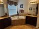 Bright bathroom featuring a soaking tub, dual vanities with granite countertops, and tile flooring at 10212 Holland Rd, Riverview, FL 33578