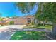 Tan single-story home featuring a well-manicured lawn and mature trees, along with a three car garage at 10212 Holland Rd, Riverview, FL 33578