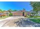 Inviting single-story tan home with a lush lawn, palm trees and a wide driveway leading to a three-car garage at 10212 Holland Rd, Riverview, FL 33578