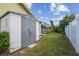 Backyard featuring green grass, the home's exterior, a storage shed and a white fence at 12371 Talpa St, Spring Hill, FL 34608