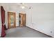 Bedroom with light gray carpet and red curtains featuring two doors with wood trim at 12371 Talpa St, Spring Hill, FL 34608