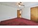 Bedroom with plush red carpet featuring two doors with wood trim and ceiling fan at 12371 Talpa St, Spring Hill, FL 34608