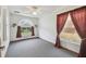 Bright bedroom with gray carpet features an arched window and cozy red curtains at 12371 Talpa St, Spring Hill, FL 34608